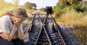 Frau sitzt verzweifelt an einer Bahngleisen-Abzweigung