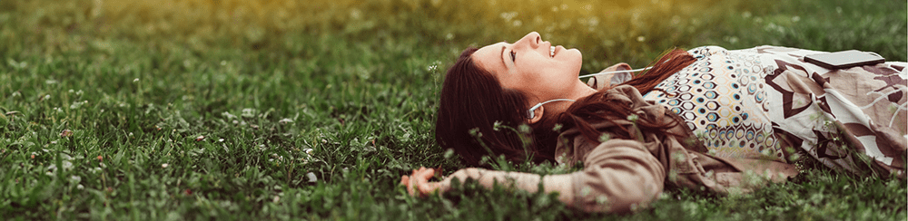Frau liegt auf einer Wiese und entspannt und ist glücklich