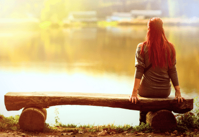 Frau, die alleine am See sitzt